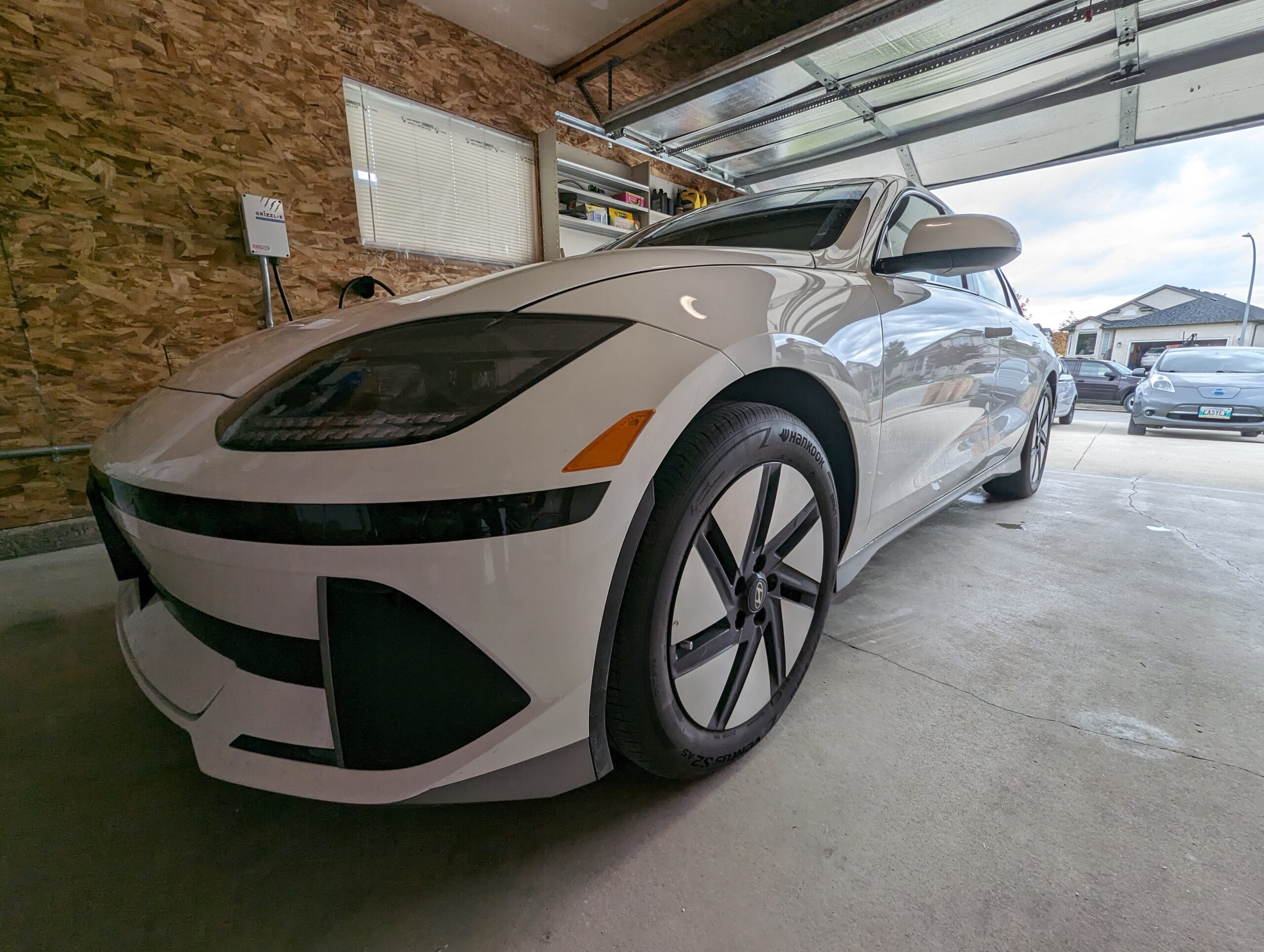 A white EV in a residential garage, connected to a Grizzl-e charger.